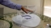 FILE- In this photo taken during a government-organized media tour, an official makes a point using a scale model of the Al-Wakra Stadium, to be used during the 2022 World Cup, in Doha, Qatar, May 4, 2015.