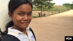 កុមារី​គុល ស្រីម៉ៅ ឈរ​នៅ​មុខ​សាលារៀន​របស់​នាង​ដែល​លោកស្រី Michelle Obama ភរិយា​ប្រធានាធិបតី​សហរដ្ឋ​អាមេរិក បាន​ទៅ​ធ្វើ​ទស្សនកិច្ច​នៅ​ខែមីនា​ឆ្នាំ២០១៥ ដើម្បី​ផ្សព្វផ្សាយ «គម្រោង​ផ្តល់​ឱកាស​ឲ្យ​ក្មេង​ស្រី​បាន​សិក្សា» «Let Girls Learn»។