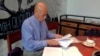 FILE - Xu Xiaoshun, the father of activism blogger Wu Gan, who was detained in what is known as the "709" crackdown, looks through documents about his son's case in a restaurant in Jiangsu Province, China, June 12, 2017.