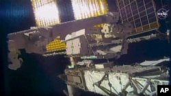 This photo provided by NASA shows NASA astronaut Chris Cassidy and NASA Flight Engineer Bob Behnken during a spacewalk outside the International Space Station, June 26, 2020. 