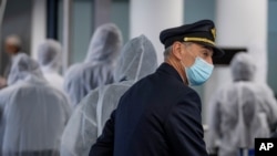 FILE - In this April 18, 2020 file photo, a pilot and crew members of South African Airways. Questions are swirling in Africa over the financial wisdom of sustaining prestige carriers amid coronavirus-related travel restrictions.