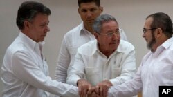 Presiden Kuba Raul Castro (tengah) mendorong Presiden Kolombia Juan Manuel Santos (kiri) dan Komandan FARC Timoleon Jimenez untuk bersalaman usai perjanjian perdamaian di Havana (23/9). (AP/Desmond Boylan)