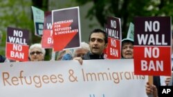 FILE - Protesters hold signs during a demonstration against President Donald Trump's revised travel ban, May 15, 2017, outside a federal courthouse in Seattle.
