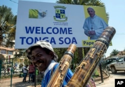 Seorang pedagang kaki lima melewati poster Paus di Antananarivo, Selasa, 3 September 2019.