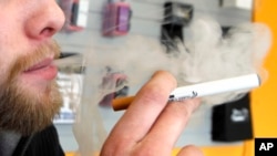FILE - A sales associate demonstrates the use of an electronic cigarette and the smokelike vapor that comes from it in Aurora, Colo., March 2, 2011.