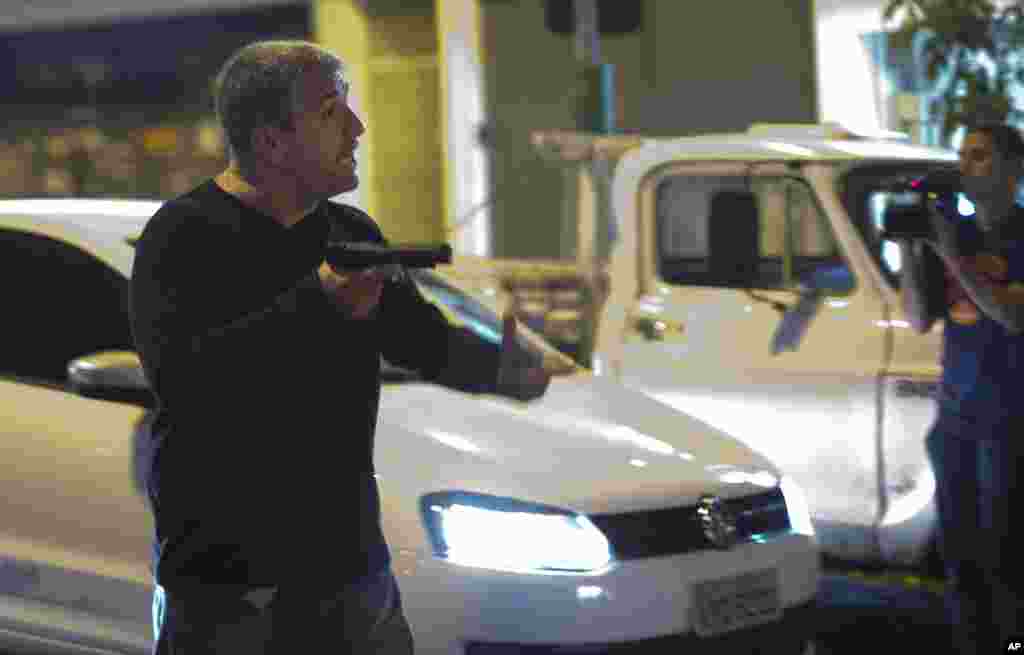 A man who identified himself as a police officer points his gun at anti-World Cup protesters blocking a road that leads to the Maracana stadium, in Rio de Janeiro, Brazil, June 15, 2014.