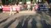 A plainclothes policeman walks past demonstrators during an anti-China protest in front of the Chinese embassy in Hanoi, May 13, 2014.