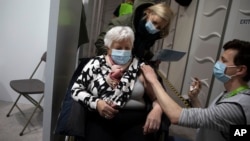 FILE - A woman receives a dose of the AstraZeneca COVID-19 vaccine at the Vaccine.