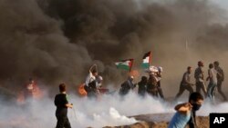 Protesters run to cover from teargas fired by Israeli troops, while others burn tires near fence of Gaza Strip border with Israel, during a protest east of Gaza City, Friday, Sept. 7, 2018. A teenager was killed and dozens of other Palestinians injured by