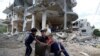 Palestinians sit on chair amid the rubble of a building which was damaged in Israeli air strikes during the Israel-Hamas fighting in Gaza May 23, 2021.