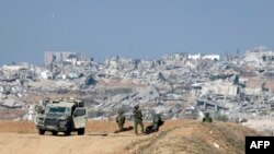 Ova slika snimljena s izraelske granice sa sjevernim pojasom Gaze prikazuje izraelske vojnike kako promatraju grad Gazu s položaja 1. januara 2024. godine, usred tekućih bitaka između Izraela i militantne grupe Hamas. (Foto: Menahem KAHANA / AFP)