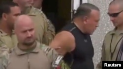 Cesar Sayoc, who was arrested during an investigation into a series of parcel bombs, is escorted from an FBI facility in Miramar, Florida, Oct. 26, 2018 in a still image from video.