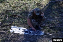 A police officer inspects pieces of a missile found in a crater that appeared during a Russian strike on the Kyiv area of Ukraine, Aug. 6, 2024.