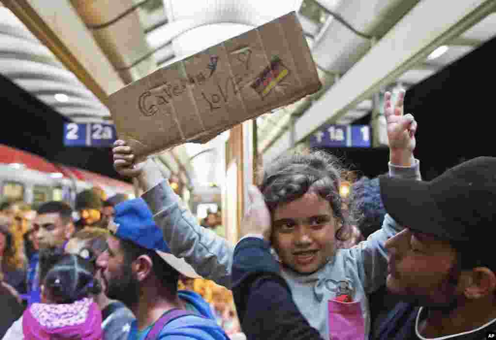Seorang gadis migran kecil mengangkat papan bertuliskan kecintaan terhadap Jerman saat ia tiba di stasiun kereta api di Saalfeld, Jerman tengah (5/9). ​(AP/Jens Meyer)