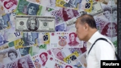 FILE - A man walks past an advertisement promoting China's renminbi (RMB) or yuan, U.S. dollar and Euro exchange services at foreign exchange store in Hong Kong, China, Aug. 13, 2015. 