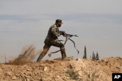 FILE - A Shi'ite fighter clashes with members of the Sunni-dominated Free Syrian Army rebel in the town of Hatita, in the countryside of Damascus, Syria, Nov. 22, 2013.