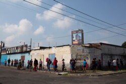 People stand in line to buy food from a small grocery store in the "La Reformita" neighborhood during a lockdown in Guatemala City, May 15, 2020.