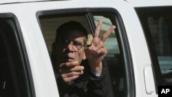 Tersangka pembajak pesawat EgyptAir, Seif Eddin Mustafa mengacungkan jari tanda damai dari dalam mobil polisi saat meninggalkan pengadilan di Larnaca, Siprus (30/3). 