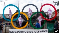 FILE - Exile Tibetans use the Olympic Rings as a prop as they hold a street protest against the holding of 2022 Winter Olympics in Beijing in Dharmsala, India, Feb. 3, 2021. 