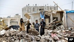 A boy and his sisters watch graffiti artists spray on a wall, commemorating the victims who were killed in Saudi-led coalition airstrikes in Sanaa, Yemen, May 18, 2015. 