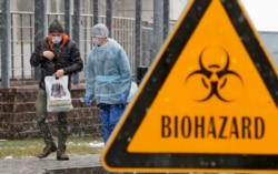 A medical worker and a man wearing face masks talk to each other at the Botkin isolation hospital, where patients are kept in isolation for possible inflection by the new coronavirus, in St. Petersburg, Russia, March 16, 2020.
