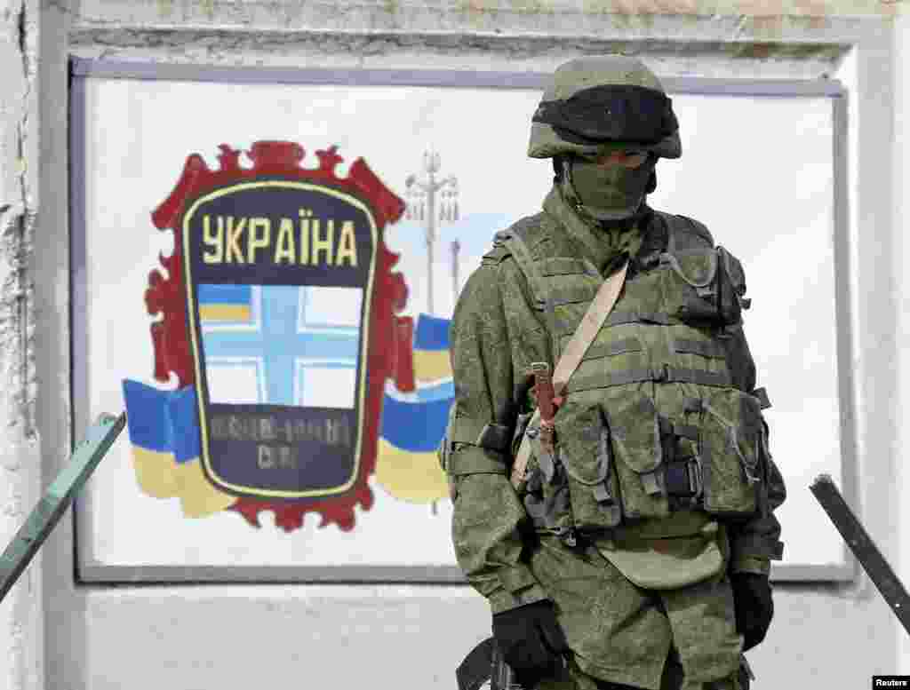 A uniformed man, believed to be a Russian serviceman, stands guard near a Ukrainian military base in Perevalnoye, outside Simferopol, March 6, 2014.