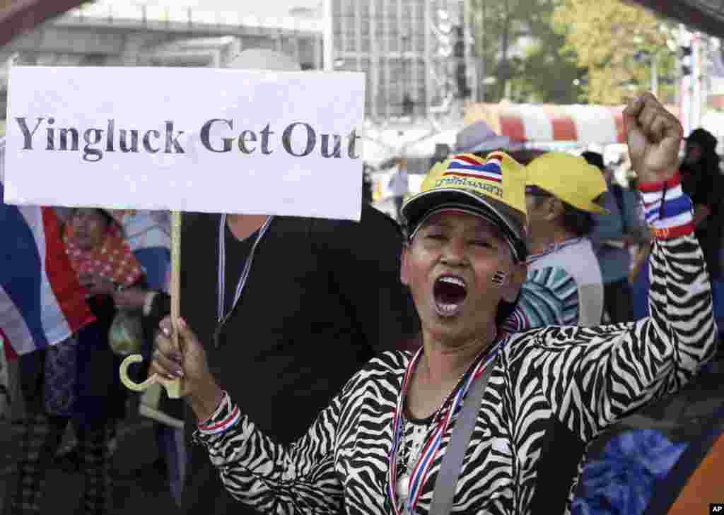 Seorang demonstran anti pemerintah membawa spanduk dan menyerukan slogan sepanjang demo di perempatan Victory Monument di Bangkok, 21 Januari 2014.