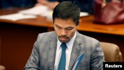 FILE - Philippine senator and boxing champion Manny Pacquiao reads his briefing materials as he prepares for the Senate session in Pasay city, Metro Manila, Philippines, Sept. 20, 2016. 