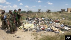Dalam gambar yang diambil dari video ini, tentara milisi Syiah berdiri di dekat sebuah kuburan masal yang diyakini berisi jenazah-jenazah tentara Irak yang dibunuh ISIS saat mereka menyerbu pangkalan militer Kamp Speicher, Juni tahun lalu.