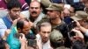 FILE - Police officers and journalists surround Mir Shakil-ur-Rahman, the owner and editor-in-chief of Geo television news channel and the Jang group of newspapers, as he leaves after court proceedings in Lahore, Pakistan, March 13, 2020.