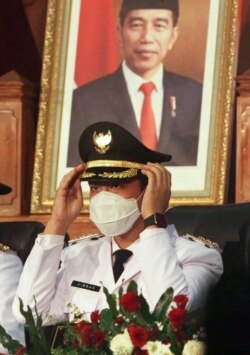 Gibran Rakabuming Raka, putra Presiden Indonesia Joko Widodo, duduk di depan potret ayahnya saat dilantik sebagai Wali Kota Solo di Jawa Tengah, 26 Februari 2021. (Foto: Anwar Mustafa / AFP)