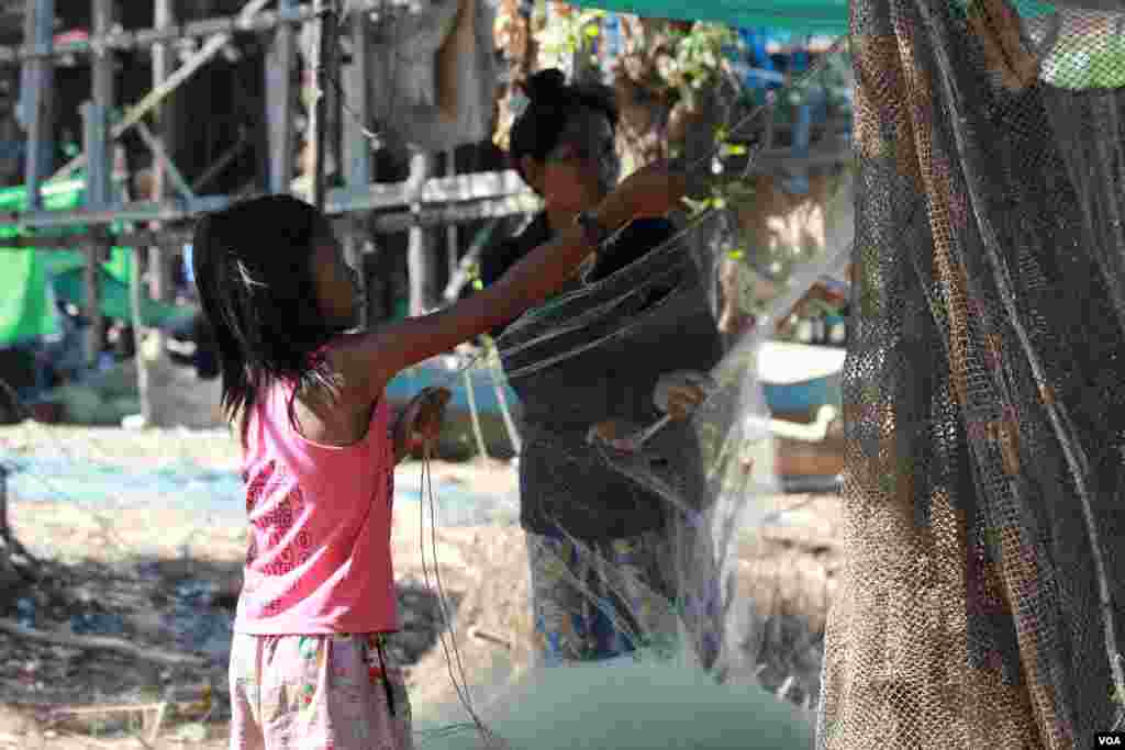 ក្មេង​ស្រី​ម្នាក់​កំពុង​ជួយ​ម្តាយ​របស់​នាង​ រៀប​ចំ​សំណាញ់​នៅ​ក្នុង​ភូមិ​កំពង់​ភ្លុក​ ខេត្ត​សៀមរាប​ កាល​ពី​ថ្ងៃ​ទី​៥​ ខែ​ធ្នូ​ ឆ្នាំ​២០១៥។​​ (នូវ​ ពៅ​លក្ខិណា/VOA)​&nbsp;