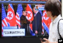 FILE - A man looks at a TV screen showing North Korean leader Kim Jong Un, left, and U.S. President Donald Trump shaking hands before their meeting in Singapore, in Tokyo, June 12, 2018.