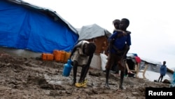 A boy carries a girl as they walk through the mud in an internally displaced persons (IDP) camp inside the U.N. base in Malakal, South Sudan, July 24, 2014. 