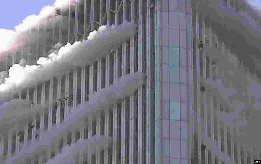 People hang from the windows of the North Tower of the World Trade Center after a hijacked airliner hit the building.