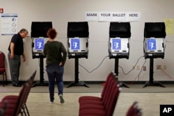 FILE - Kelly Monroe, investigator with the Georgia Secretary of State office, takes a look at a new voting machine that produces a paper record being tested at a polling site in Conyers, Ga., Oct. 19, 2017.