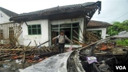 Seorang polisi sedang menginspeksi kerusakan salah satu rumah jemaah Ahmadiyah yang diserang massa di Pandeglang, Banten (7/2).