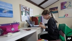 FILE - In this March 19, 2020 file photo, a student takes a class online at her home in San Francisco. 
