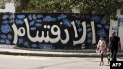 A Palestinian man and his daughter walk past a graffiti reading in Arabic ''Division'' in Gaza City, on Sept. 17, 2017, after Hamas announced it had agreed to steps toward resolving a decade-long split with the Fatah movement.