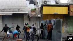 Warga Palestina melemparkan batu-batu dalam bentrokan dengan tentara Israel di kota Hebron, Tepi Barat, setelah Arafat Jaradat, tewas di penjara Israel, Minggu (24/2). (AP/Nasser Shiyoukhi)