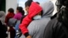 Sejumlah keluarga tampak menunggu di kantor imigrasi di Bandara Internasional La Aurora di Guatemala pada 4 Agustus 2021. Para keluarga tersebut dideportasi dari AS setelah terkena dampak dari kebijakan Title 42. (Foto: Reuters/Luis Echeverria)