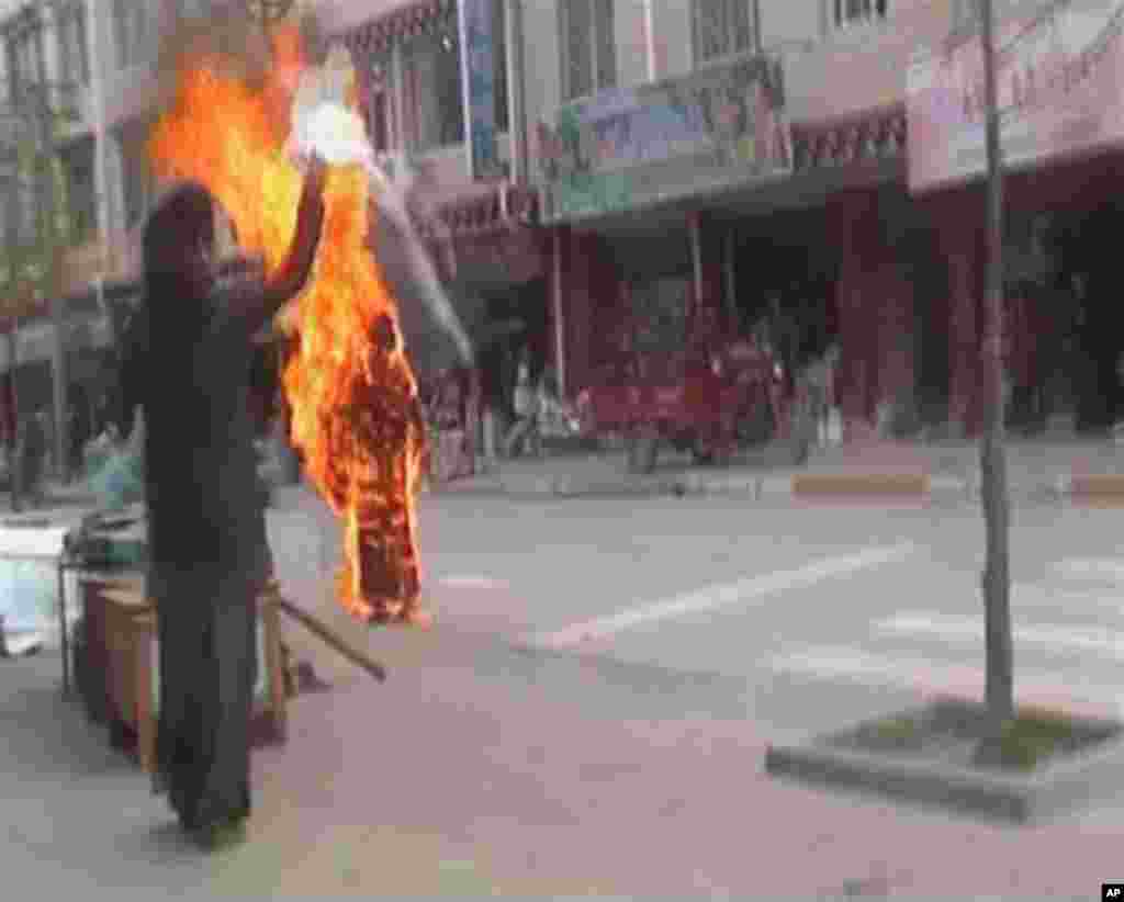 A woman throws a white scarf over Tibetan Buddhist nun Palden Choetso as she burns on the street in Daofu, or Tawu in Tibetan, in this still image taken from video. The 35-year-old Tibetan Buddhist nun burned herself to death on the public street in the