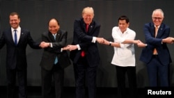 Presiden Donald Trump tersenyum bersama pemimpin lain, termasuk Perdana Menteri Rusia Dmitry Medvedev, Perdana Menteri Vietnam Nguyen Xuan Phuc, Presiden Filipina Rodrigo Duterte dan Perdana Menteri Australia Malcolm Turnbull melakukan jabat tangan khas ASEAN pada KTT ASEAN di Manila, Filipina, 13 November 2017. 