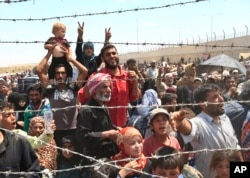 FILE - Syrian refugees gather at the Turkish border as they flee intense fighting in northern Syria between Kurdish fighters and Islamic State militants in Akcakale, southeastern Turkey.