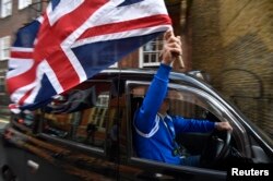 A taxi driver holds a Union flag, as he celebrates following the result of the EU referendum, in central London, Britain June 24, 2016.