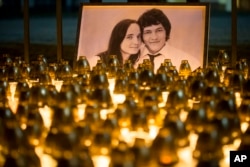 FILE - Light tributes are placed during a silent protest in memory of murdered journalist Jan Kuciak and his girlfriend, Martina Kusnirova, seen in the photograph, in Bratislava, Slovakia, Feb. 28, 2018.