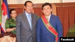រូបលោក កុយ គួង (ស្តាំ) អ្នកនាំពាក្យ​ក្រសួង​ការបរទេស និង​សហ​ប្រតិបតិ្តការ​អន្តរជាតិ ឈរ​ថតរូប​ជាមួយ​លោក ហ៊ុន សែន នាយក​រដ្ឋមន្រ្តី​នៃ​ប្រទេស​កម្ពុជា។ (រូបថត​ពី​ទំព័រ​ហ្វេស​ប៊ុក Koug Koy)