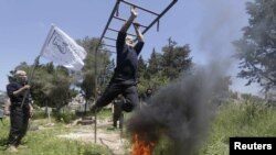 Rebel fighters from 'the First Regiment', part of the Free Syrian Army, swing from bars as they participate in a military training in the western countryside of Aleppo, Syria, May 4, 2015. REUTERS/Hosam Katan
