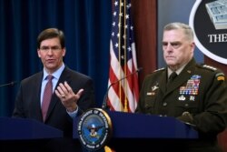 Defense Secretary Mark Esper, left, standing with Joint Chiefs​ Chairman Gen. Mark Milley, speaks during a news conference at the Pentagon in Washington, Dec. 20, 2019.