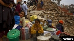 Warga Nepal bersama barang-barang mereka tinggal di luar sebuah kuil yang hancur di lapangan Bashantapur Durbar, Kathmandu, Nepal (25/4).